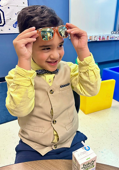 Young Declan dressed up in dress clothes putting sunglasses on