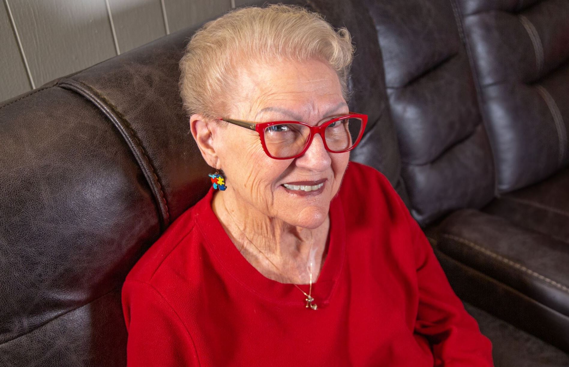 Jan Jodan sitting on a coach looking at the camera with red glasses.