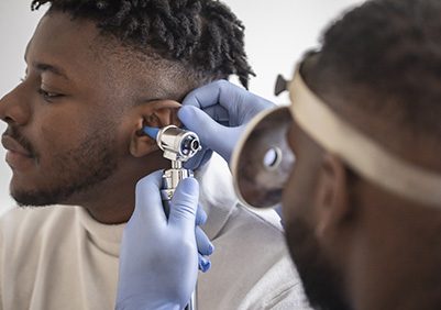 Black man having his ears look at by an ENT