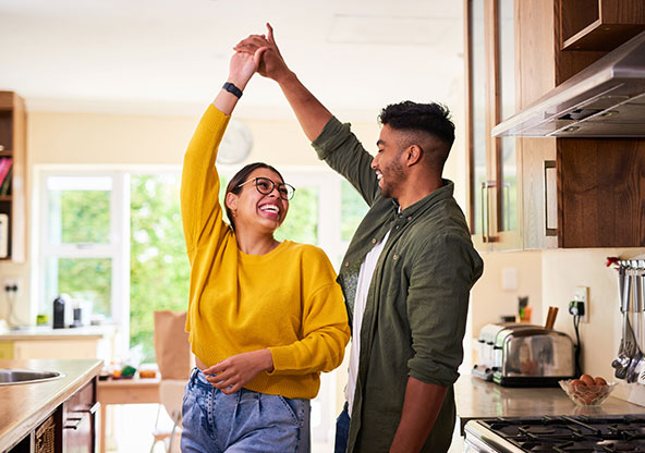 A dad holds his baby while cooking at the stovetop